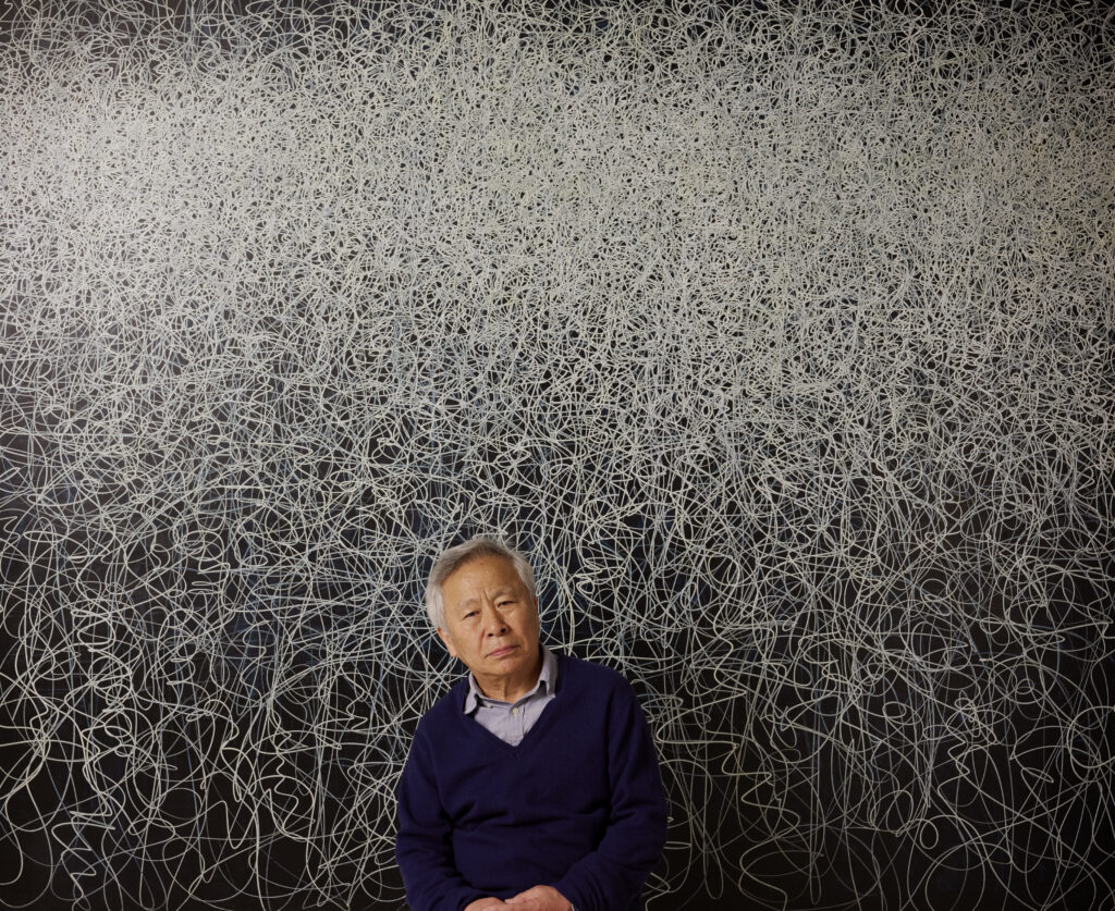 Il Lee poses with “IW-2201” by Il Lee, 2022 - Acrylic and oil on canvas, 82 x 100 in. (208.3 x 254 cm) (Photo courtesy of the Vilcek Foundation)
